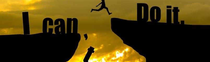 silhouette of man jumping across cliff edges