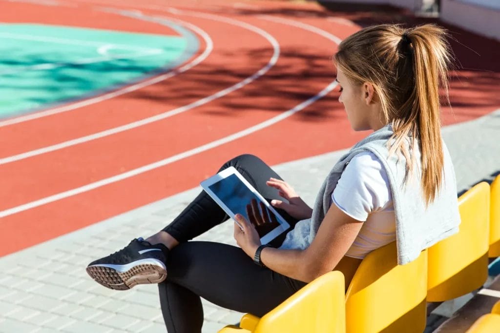 Personal trainer at a stadium doing SEO on her tablet