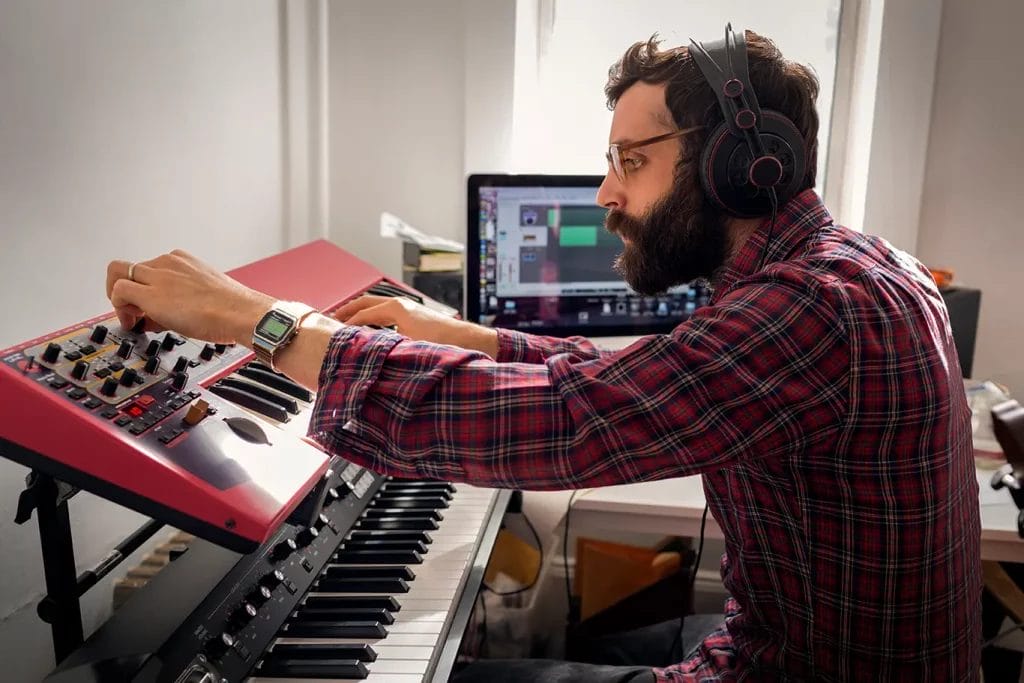 Musician turning knobs on an electric keyboard.