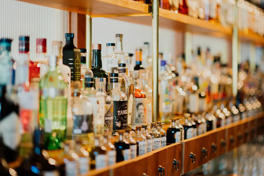 Bottles of liquor and bitters on a wooden shelf.