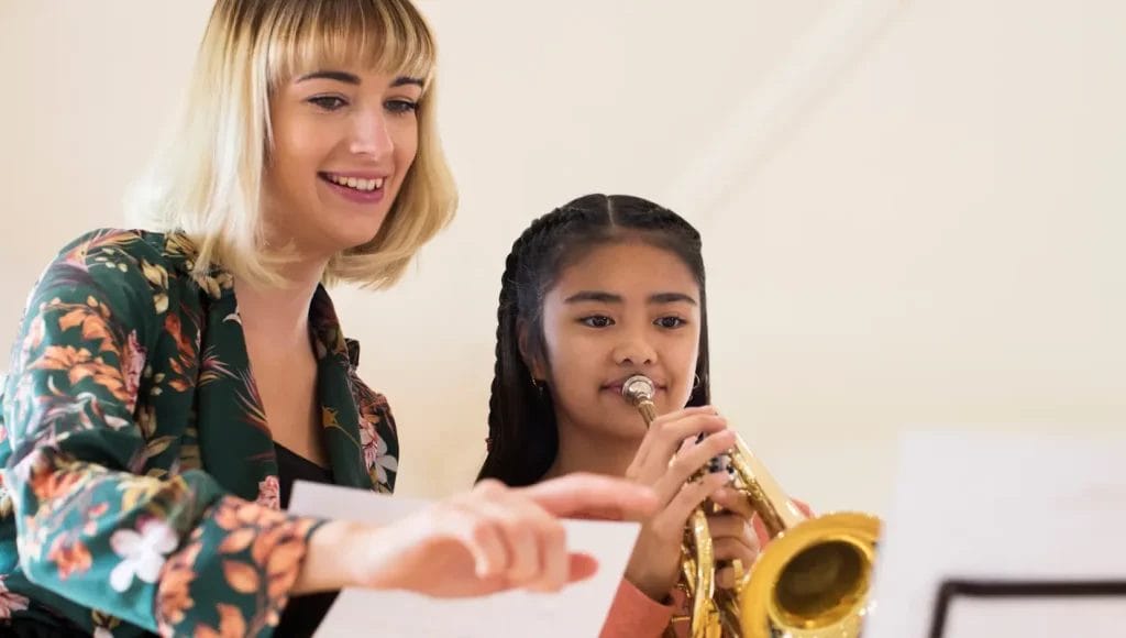 Music teacher teaching student how to blow horn