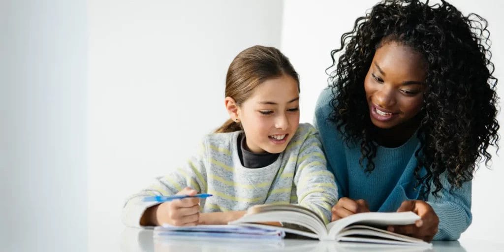 A tutor reading a passage out of a book with a student.