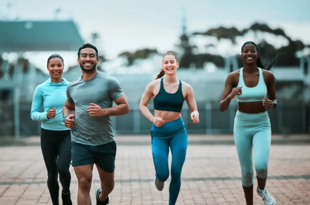 Group of four wearing blue athletic outfits running on paved path