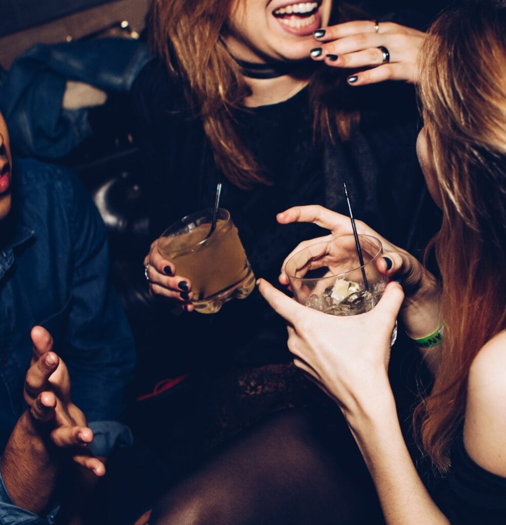 Three people laughing and holding drinks.