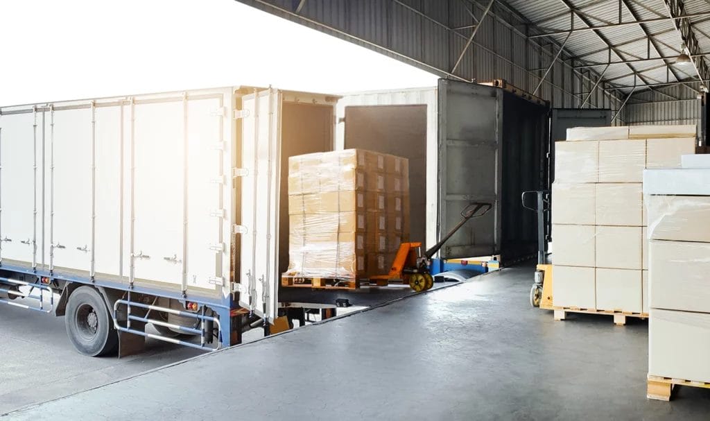 A shipping truck is being loaded with pallets full of boxes wrapped and packaged for transit.