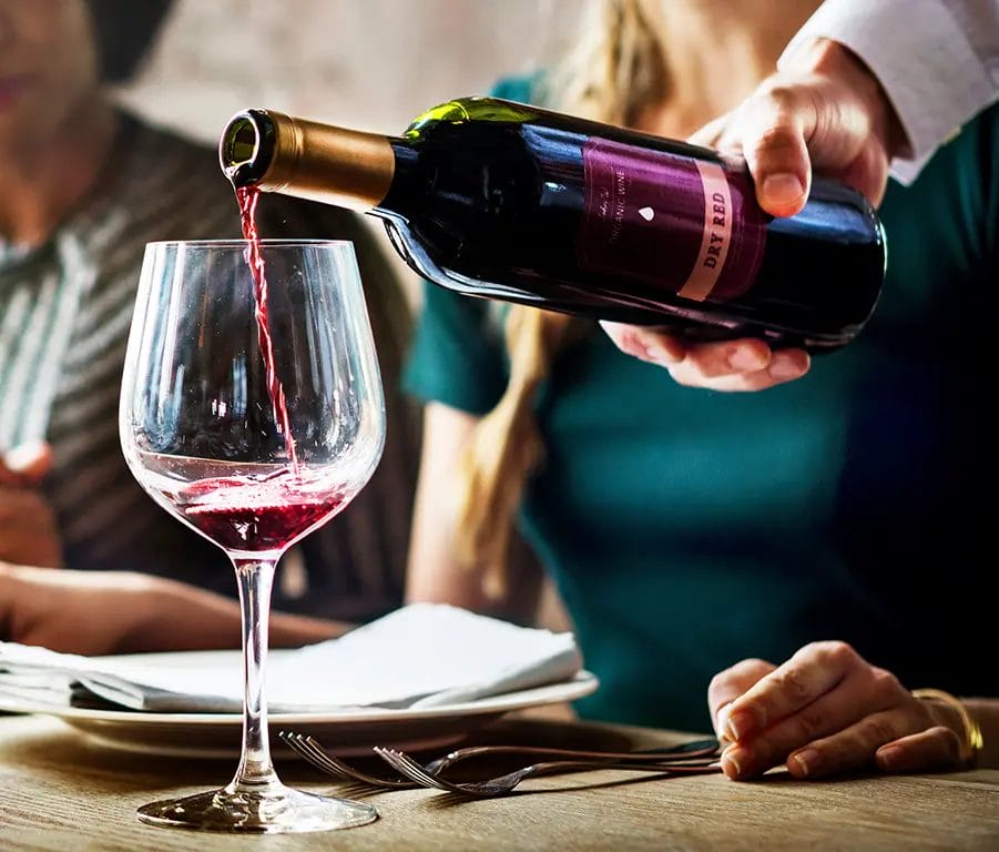 Server pouring wine into a glass.