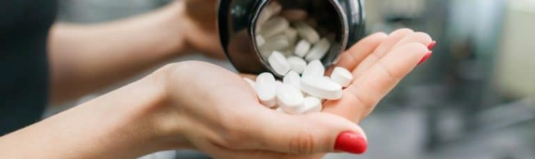 woman pouring vitamins into hand