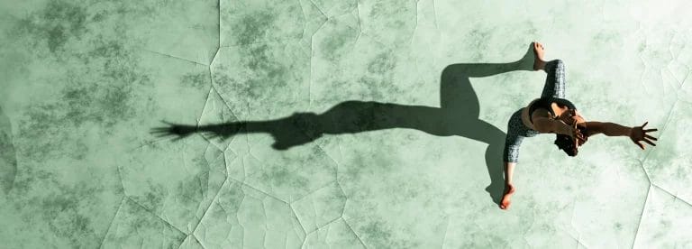A yoga instructor poses on a green glass outdoor surface