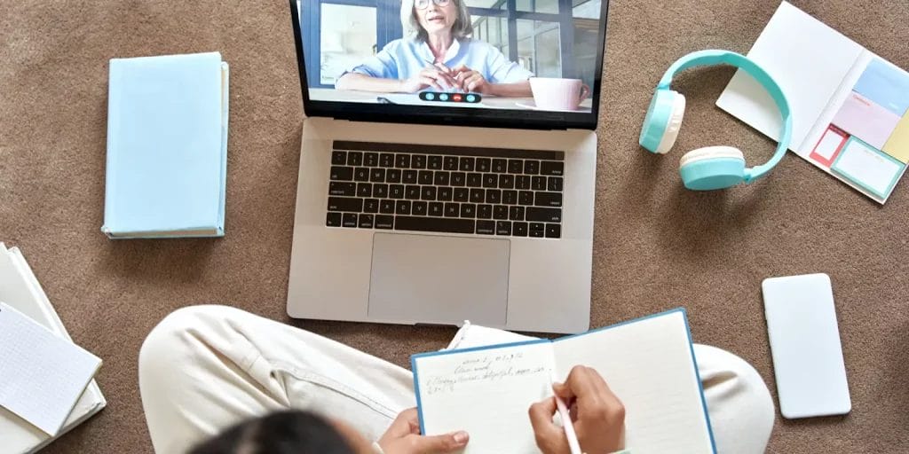 Student in a lesson with an online tutor writing in their notebook.