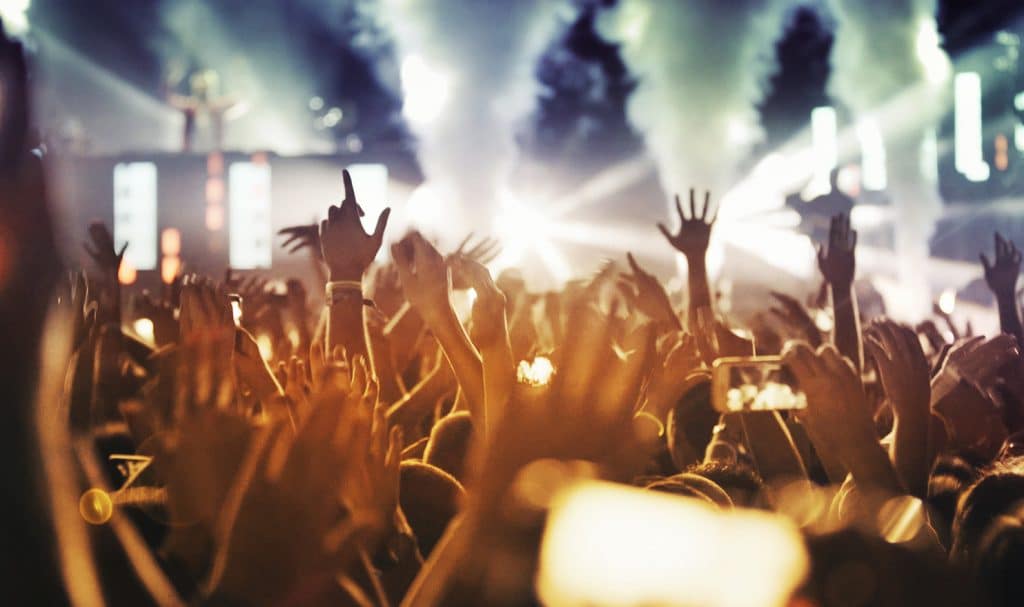 people at a concert raising their hands in the crowd