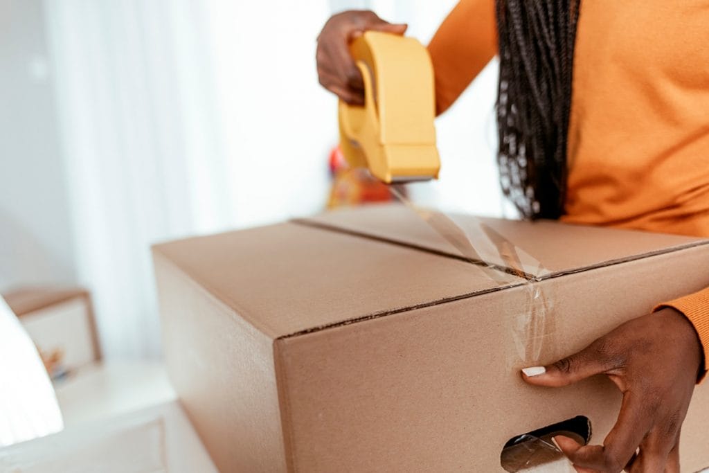 A woman places a product into a cardboard shipping box