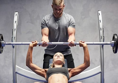 man spotting woman while she lifts weights