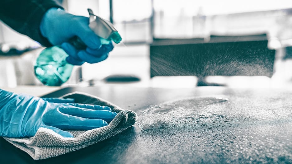 spraying cleaner and wiping with rag