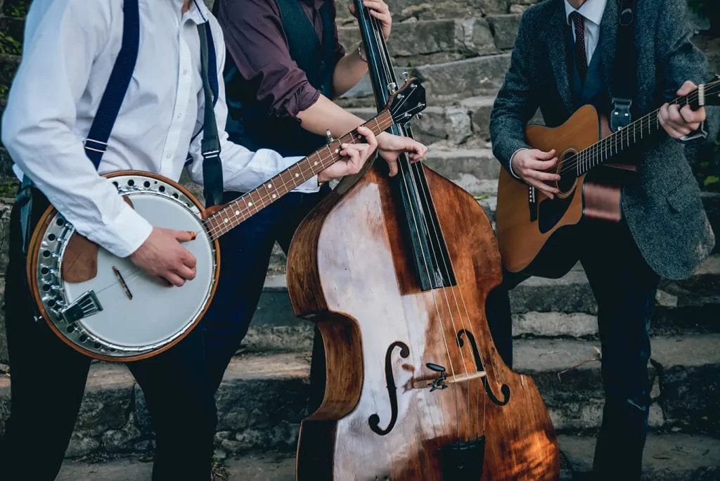 A trio of musicians in neutral-toned formal attire, playing a banjo, a bass, and a guitar.