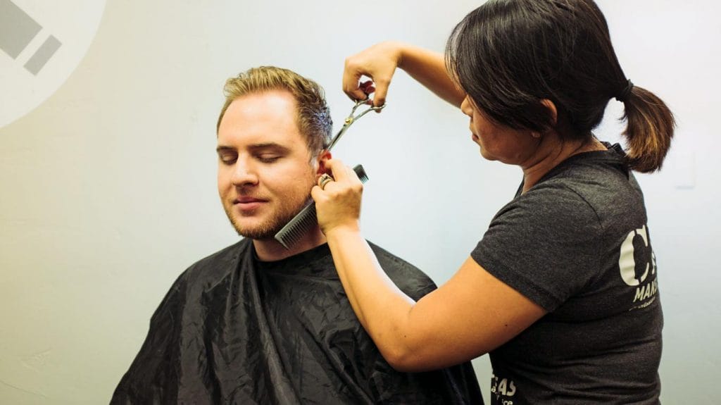 Cosmetologist trimming man's hair