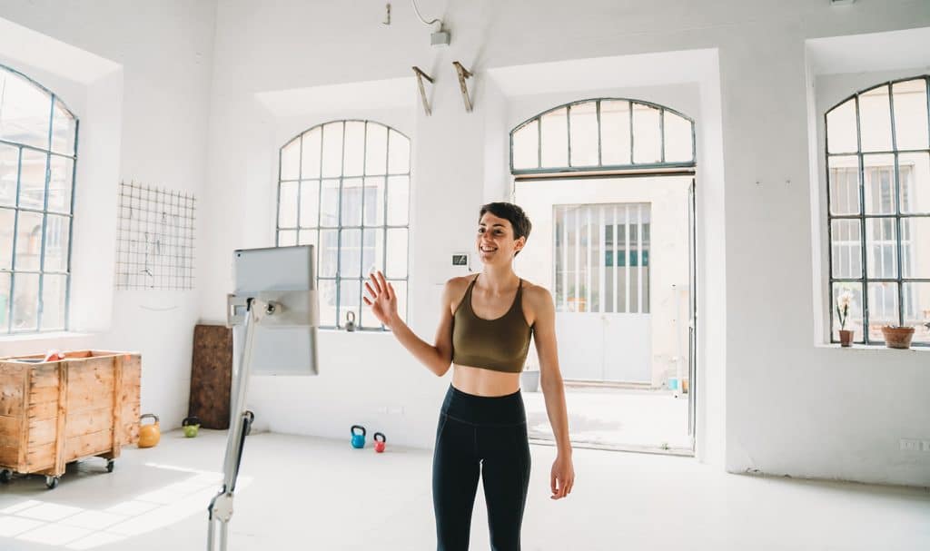 A virtual fitness instructor says hello to her clients as she starts recording a training video she will share with her clients.