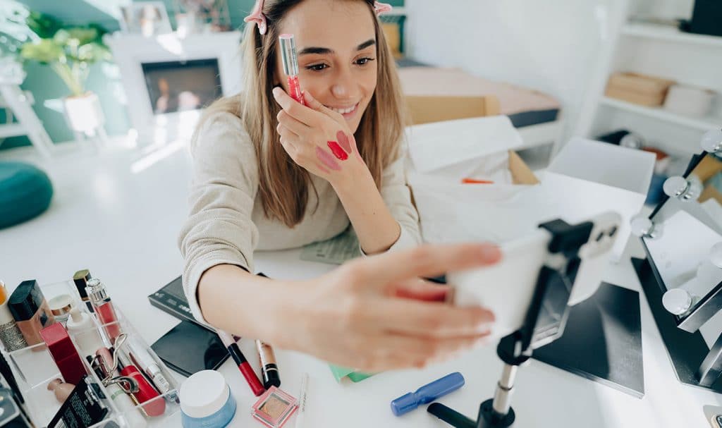 A young girl poses with makeup for her phone as she prepares to share this new product with all of her followers on social media.