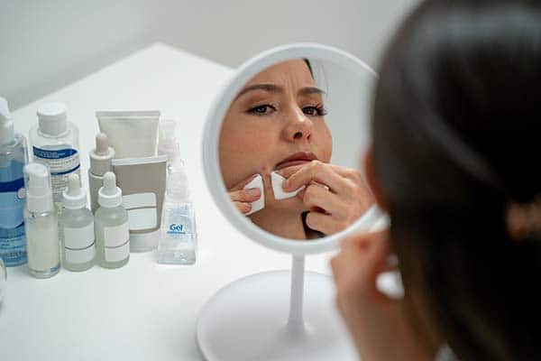 woman picking face in mirror