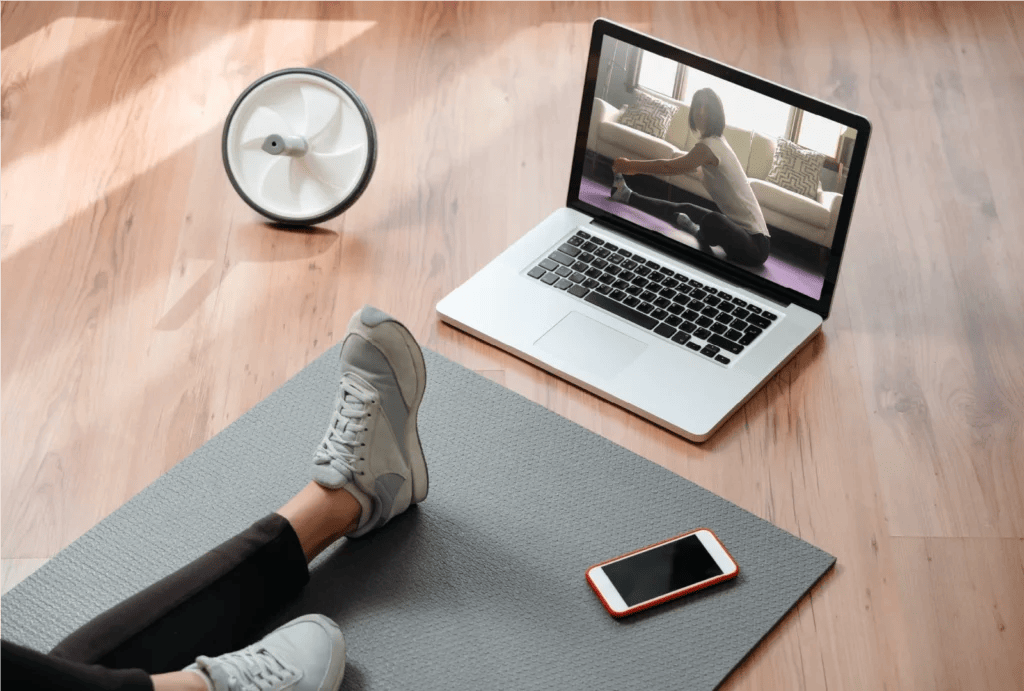 A woman sitting in front of her laptop guiding an online fitness class