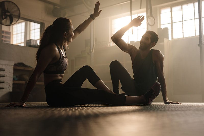 A personal trainer high-fives a client.
