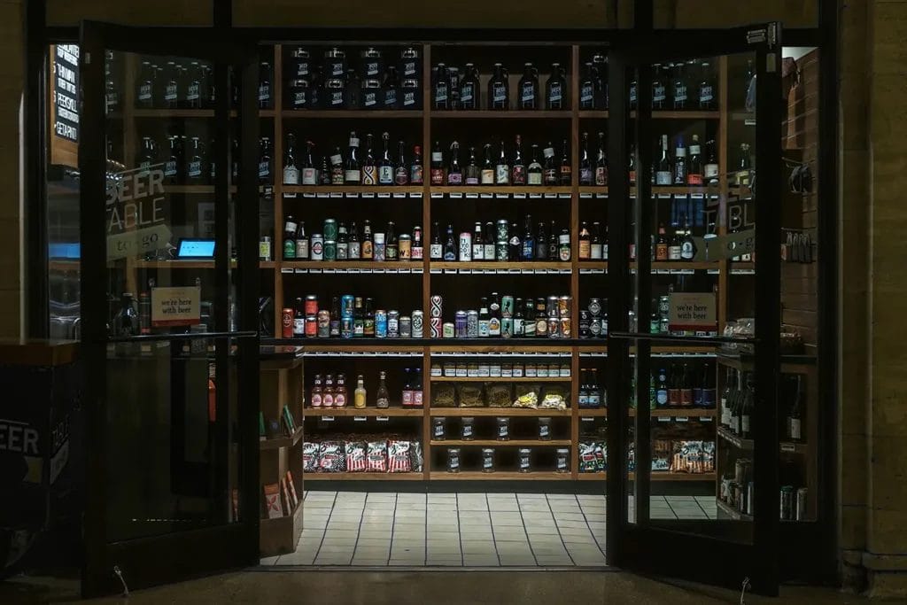 Shelves full of various kinds of alcohol seen through the open doorway of a liquor store.