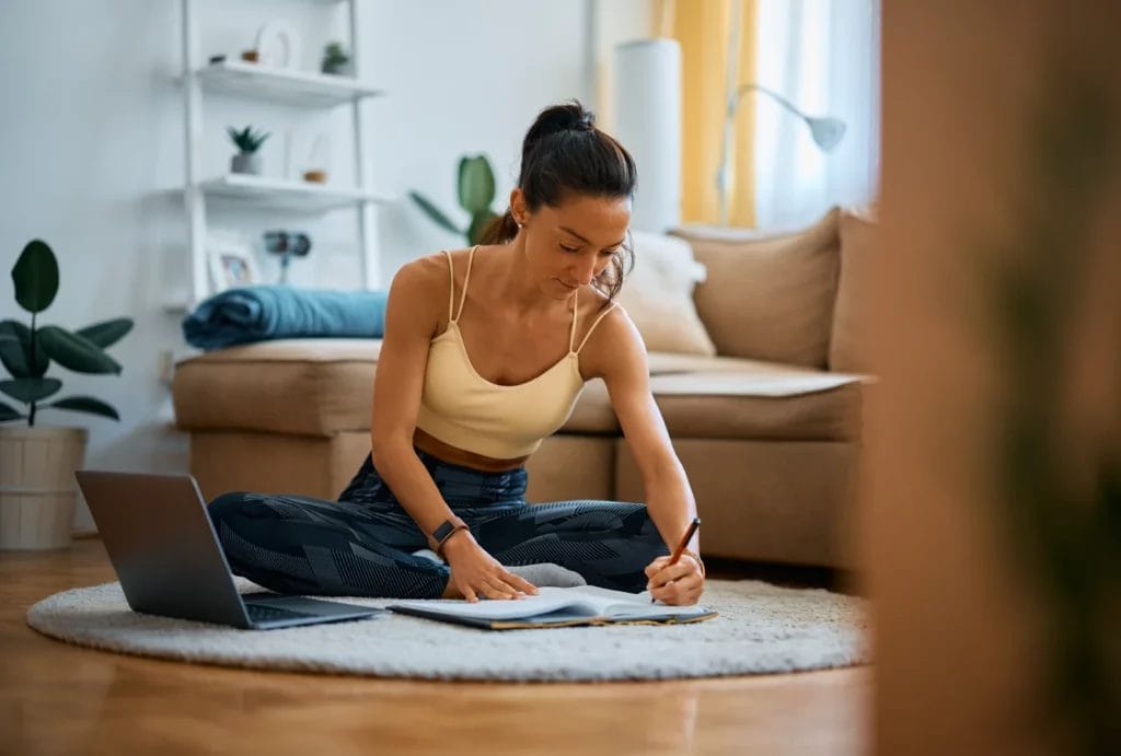 a woman writing in a notebook preparing a workout plan