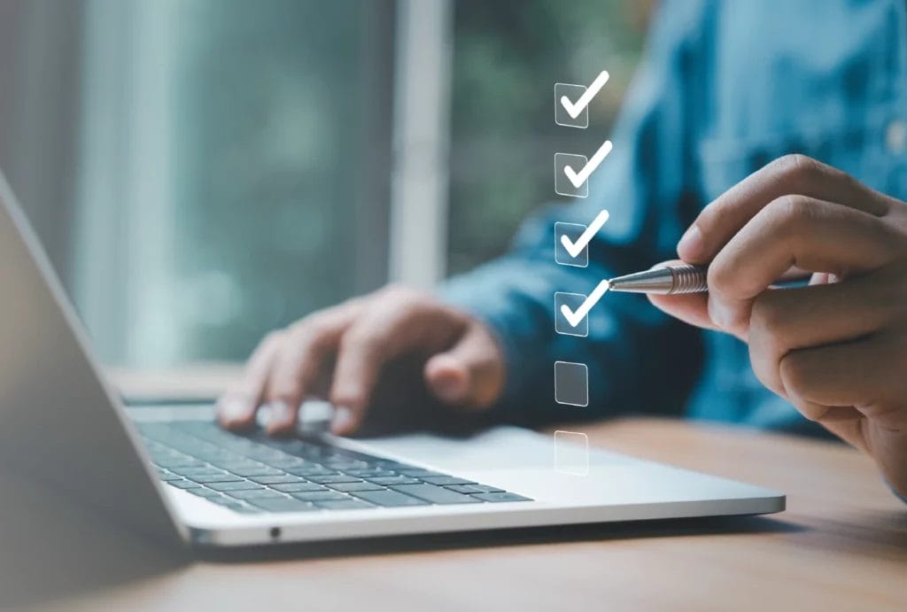 Person using a laptop checking off floating boxes, concept of fulfilling requirements