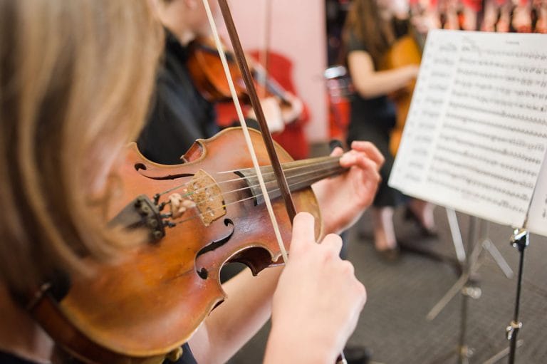 A violinist learns a new piece of music from a music teacher.