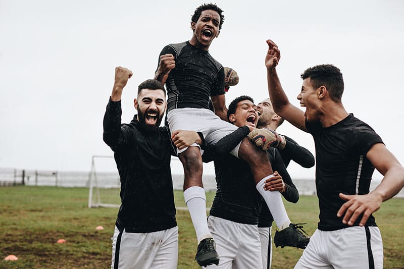 A soccer player is hoisted up in victory.