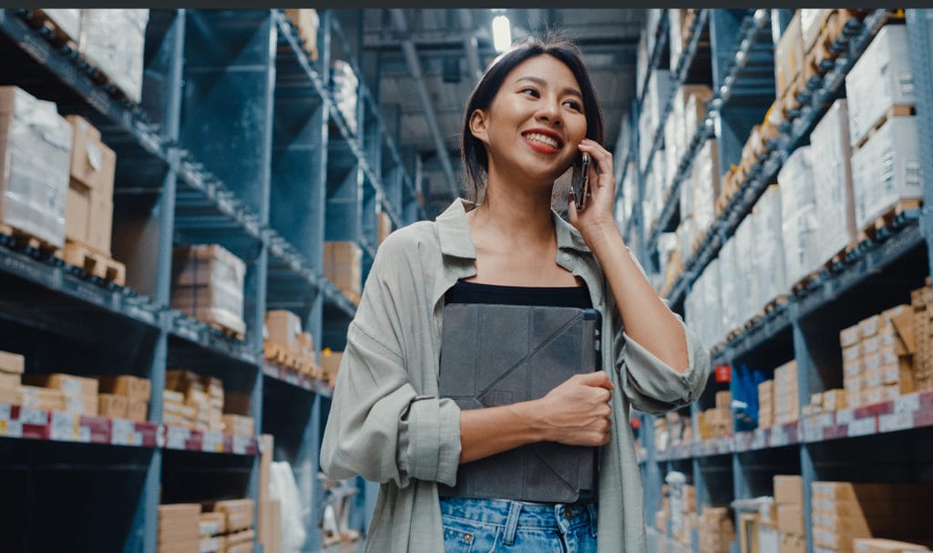 A woman talks on the phone in a warehouse.