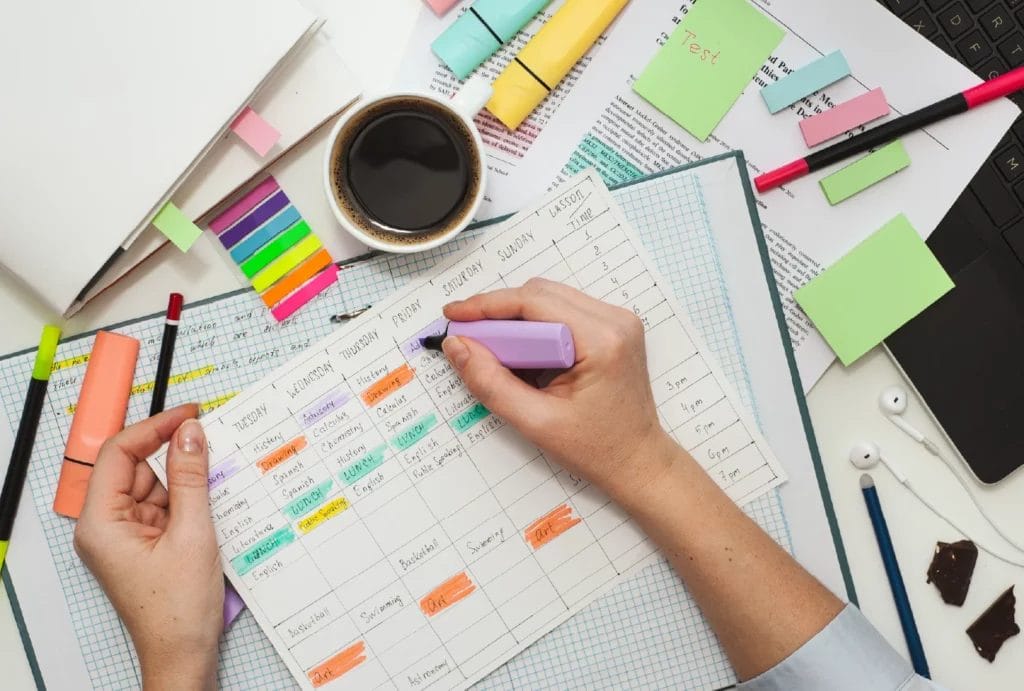 Concept of lesson planning, featuring hands surrounded by sticky notes and folders highlighting activities on a calendar