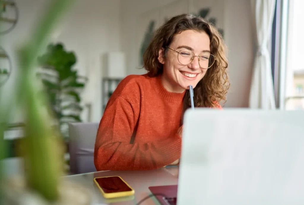 Online student smiles while working on laptop at home