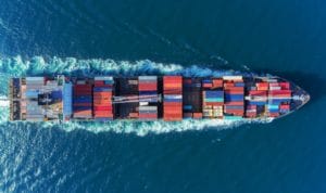 The overhead view of a cargo ship full of colorful shipping containers transporting products overseas with product liability insurance.