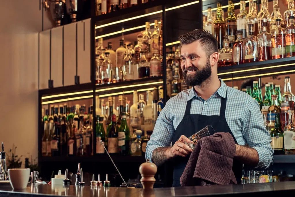 Bartender wiping a glass with cloth behind counter