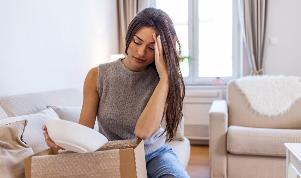 A frustrated woman is looking at a bowl that was damaged during shipping. Product liability insurance may protect against this type of claim.