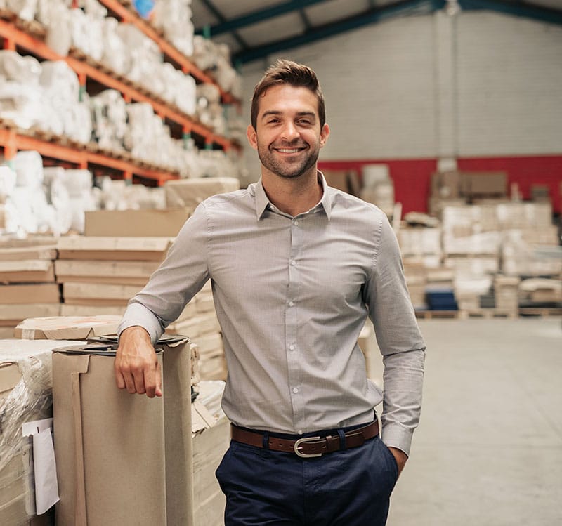 A distributor smiles inside of a warehouse.