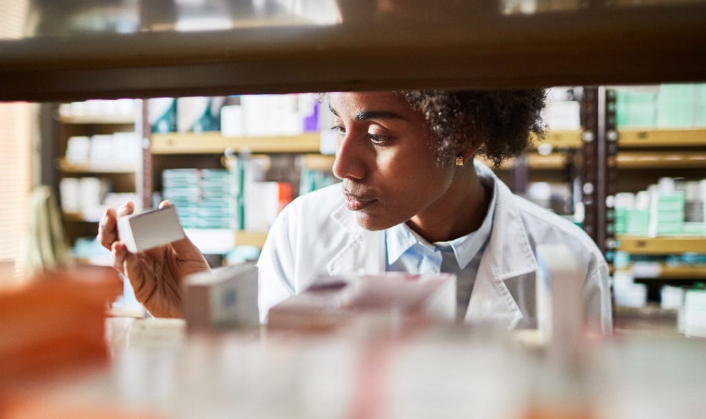 An inspector is looking at a box of supplements to see if a wholesaler is improperly storing them in their warehouse as part of a product liability claim.