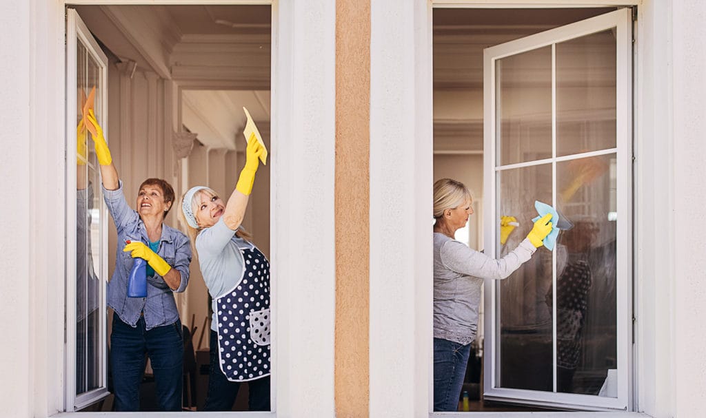 Three employees from a small cleaning business are washing the windows of a customer's home.