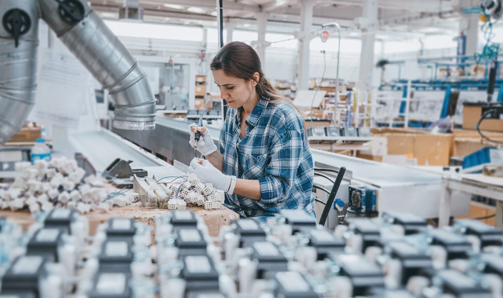 A production line employee is assembling parts of a product in a manufacturing plant.