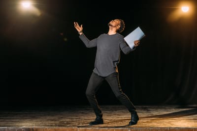 actor holding script on stage doing a performance or rehersal