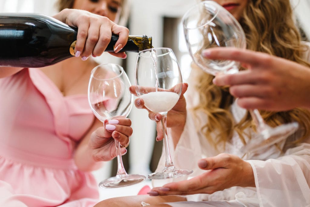Group on bachelorette trip pouring wine into glasses