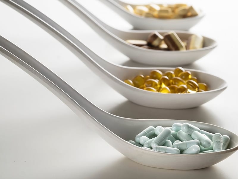 spoons full of supplements sit on a white background.