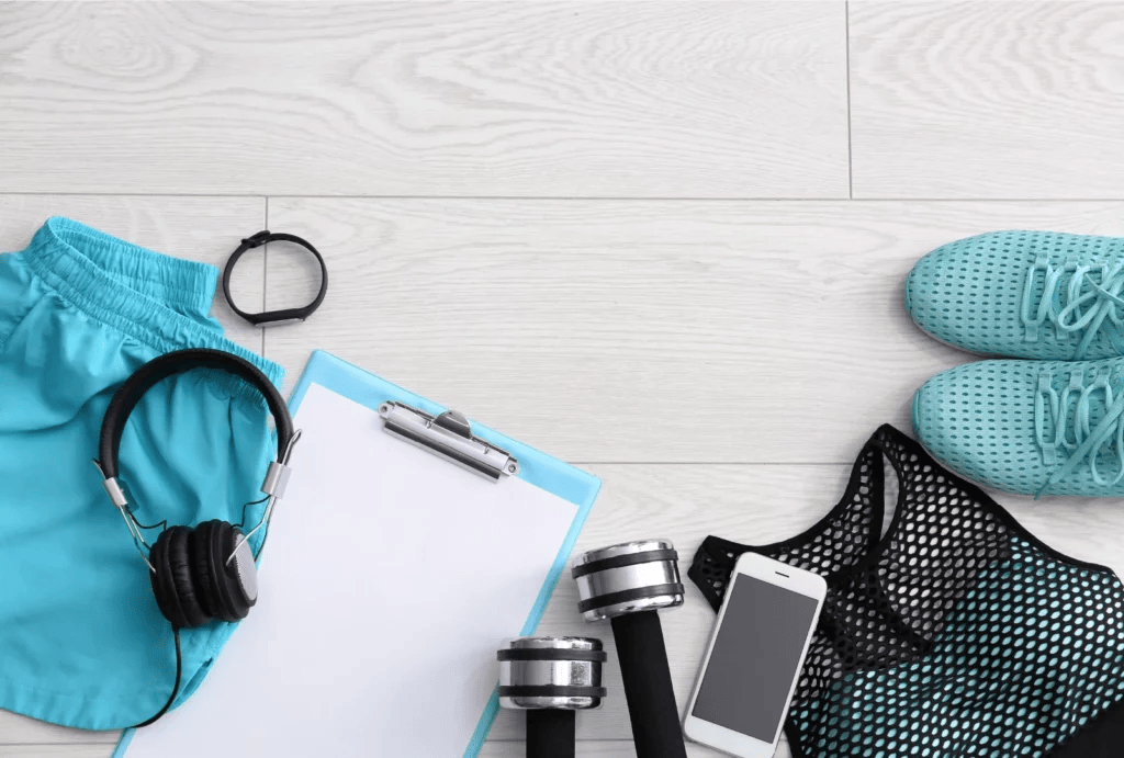 A variety of blue workout items and clothes arranged on a light grey wood floor.
