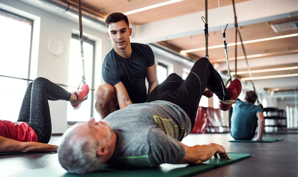 A fitness trainer helps a man workout.