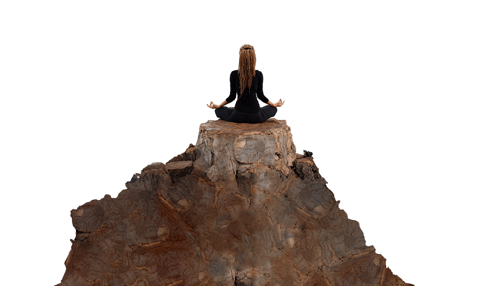 A yoga teacher is cross legged on the top of a small butte.