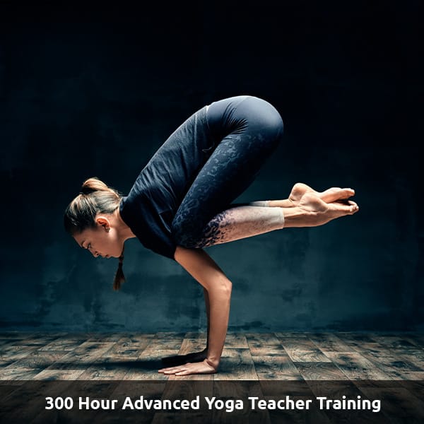 A Yoga instructor poses in an advanced yoga pose with their feet in the air. Text Reads: 300 Hour advanced Yoga Teacher Training.