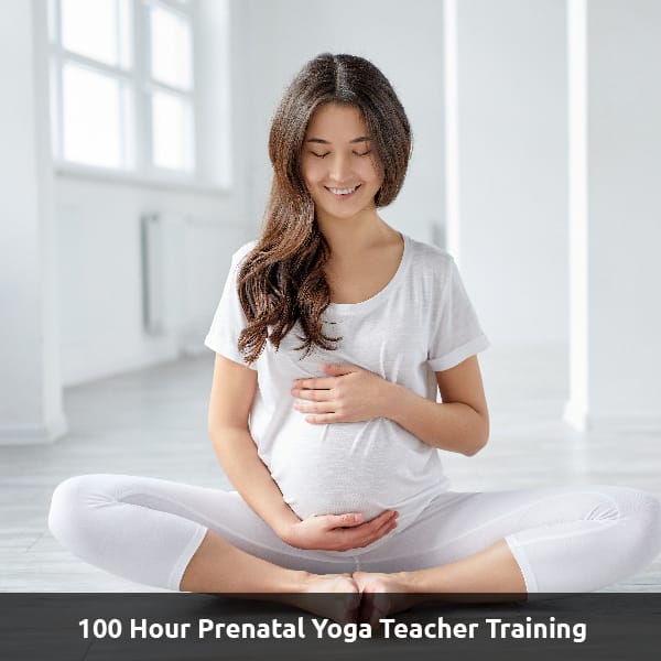 A pregnant person holds their tummy sitting cross-legged. Text Reads: 100 Hour Prenatal Yoga Teacher Training.