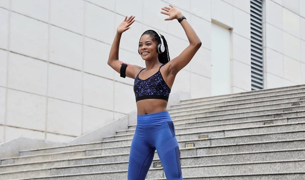 Woman in blue athletic gear doing jumping jacks.