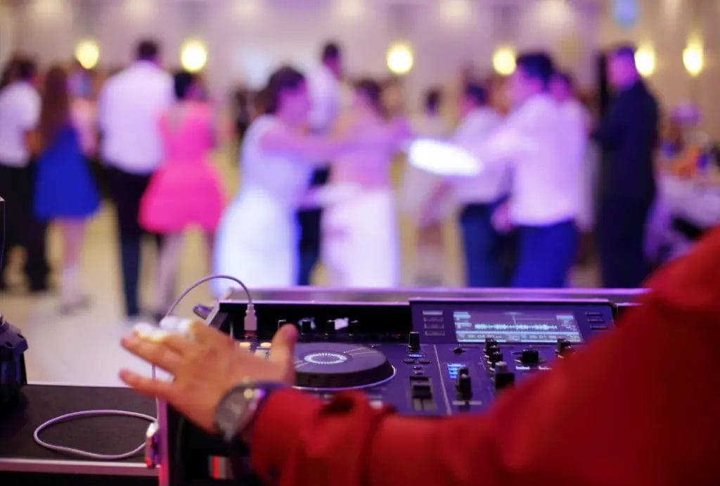 A wedding DJ spinning tracks with people on the dance floor