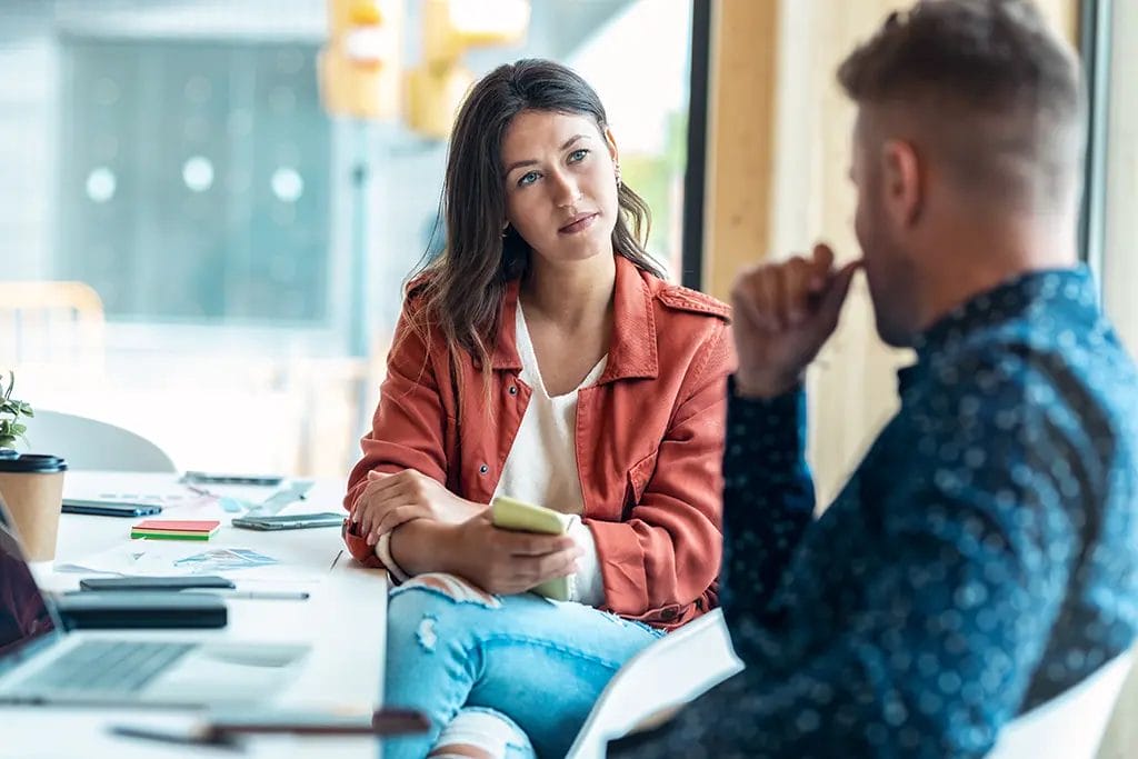 A mentor and client sitting around a conference table having a discussion.